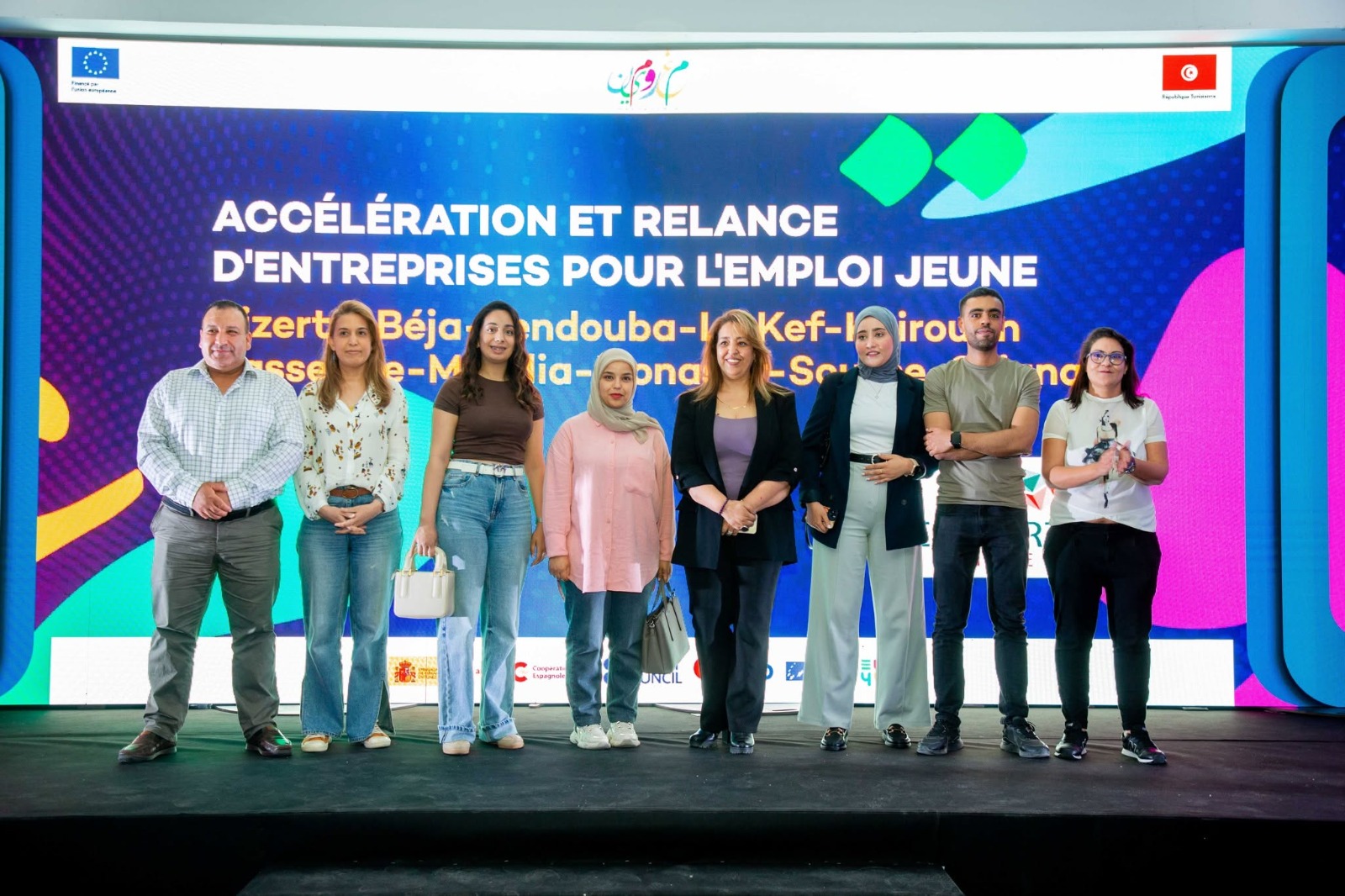 Un groupe de personnes de l'Équipe Redstart sur scène devant un grand écran affichant des visuels
